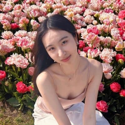 Tiffany Yan smiling while seated in a field of pink flowers